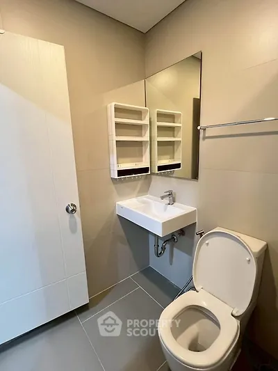 Modern bathroom with sleek fixtures and neutral tones, featuring a wall-mounted sink and toilet.