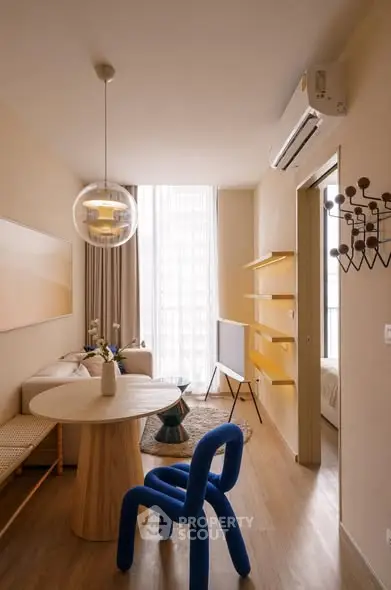 Modern living room with unique blue chair and stylish decor, featuring natural light and contemporary design.