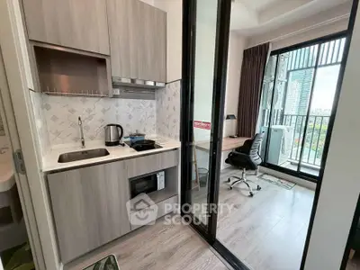 Modern compact kitchen with open layout and balcony view in urban apartment