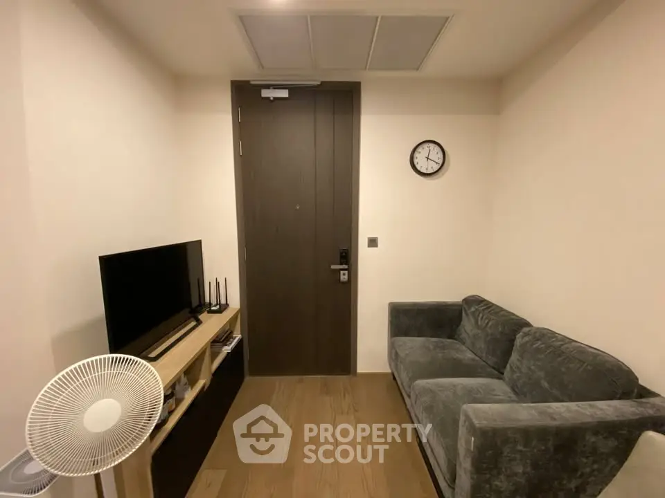Cozy living room with modern decor, featuring a plush sofa, flat-screen TV, and stylish wooden flooring.
