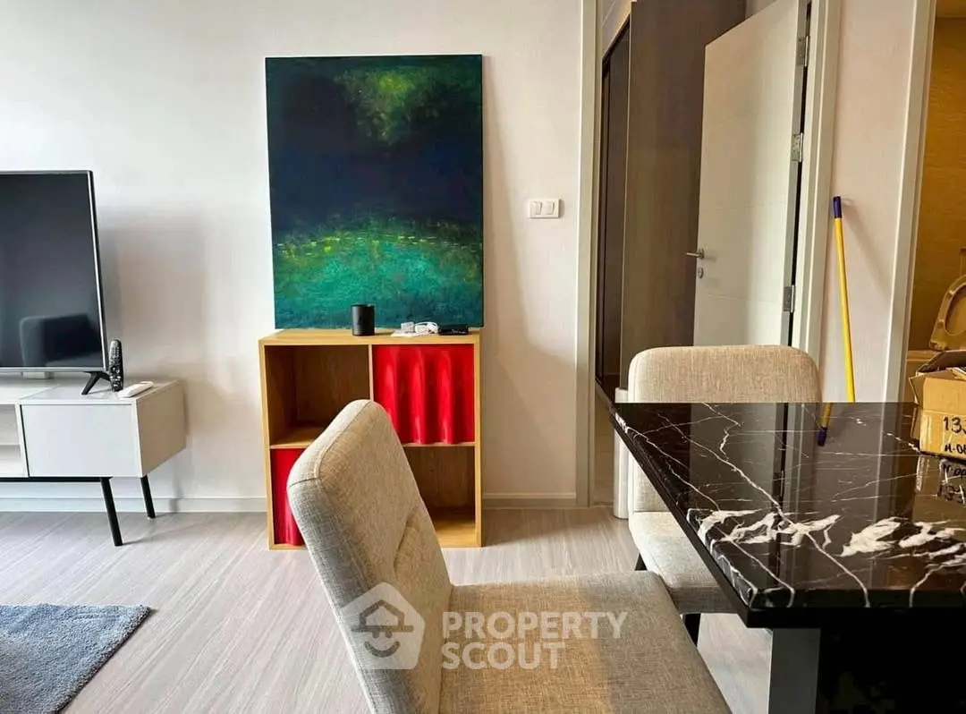 Modern living room with stylish furniture and abstract art, featuring a sleek TV stand and elegant dining area.