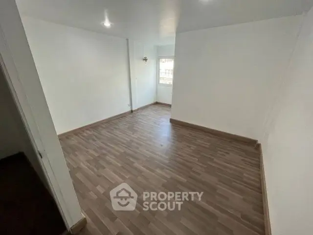 Spacious empty room with wooden flooring and white walls, ideal for customization.