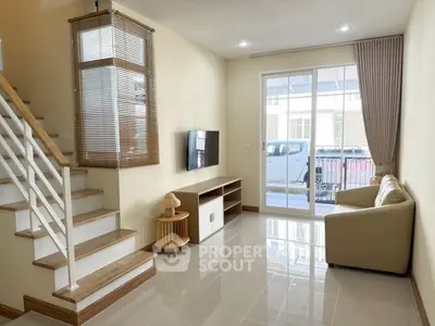 Bright modern living room with staircase and large window, perfect for family gatherings.