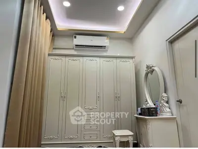 Elegant bedroom with ornate wardrobe and vanity, featuring soft lighting and neutral tones.