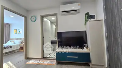 Modern living room with TV, air conditioning, and view into bedroom and bathroom.