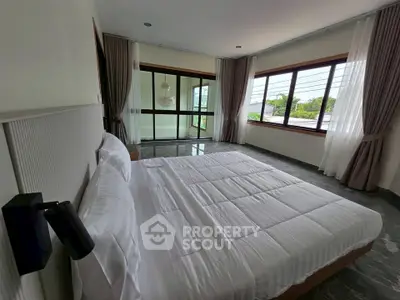 Spacious bedroom with large windows and elegant decor, offering a serene and bright atmosphere.