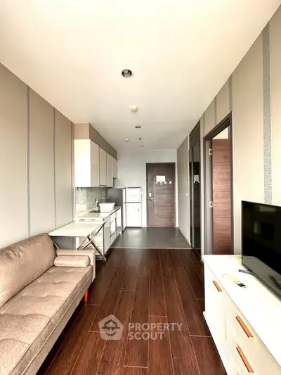 Modern apartment interior with sleek kitchen and cozy living area, featuring wooden flooring and contemporary design.