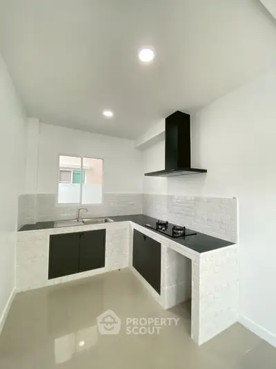 Modern kitchen with sleek black countertops and gas stove in a bright, minimalist design.