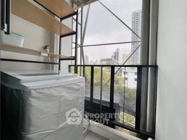 Compact balcony with washing machine and city view, ideal for urban living.