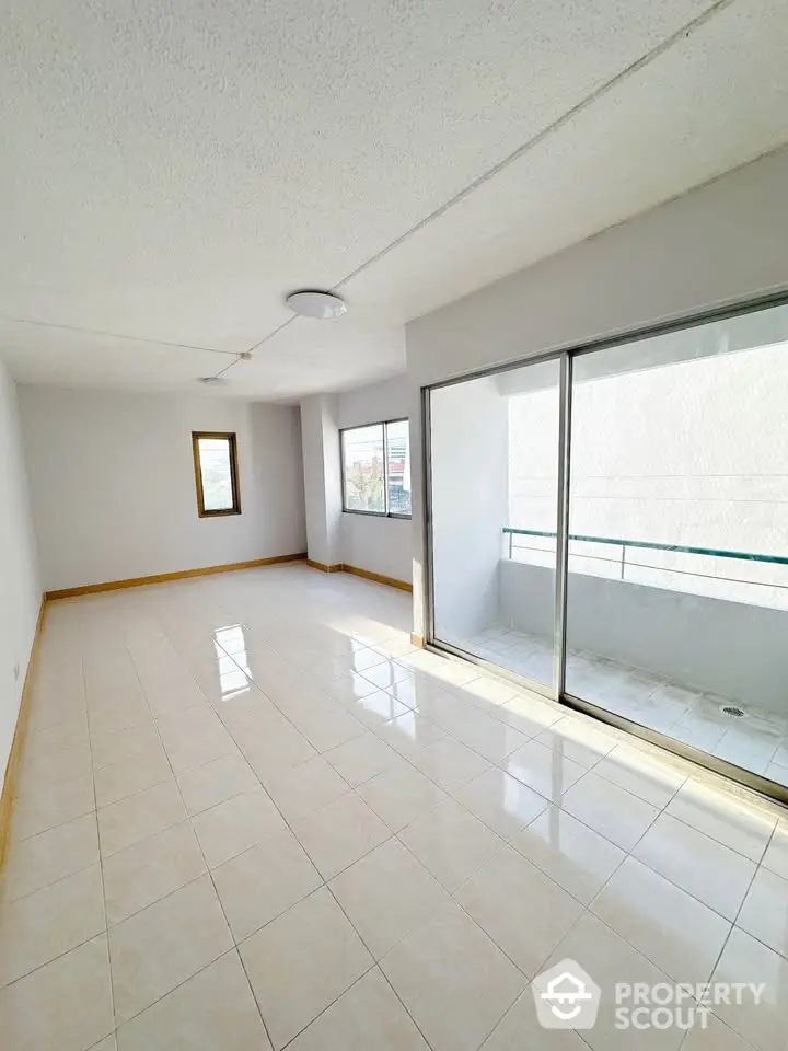 Spacious sunlit living room with balcony access and large windows