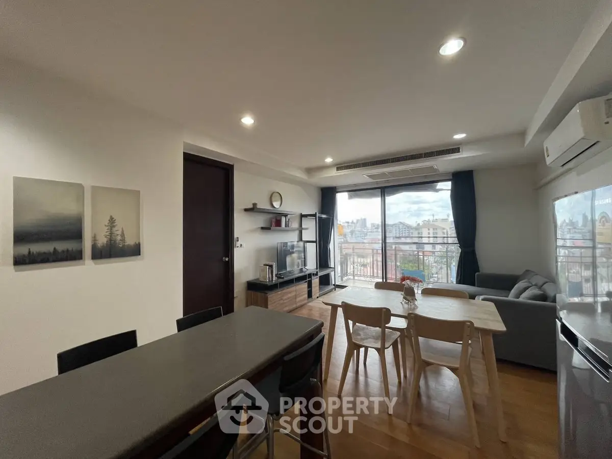 Spacious modern living room with dining area and city view, featuring sleek furniture and natural light.