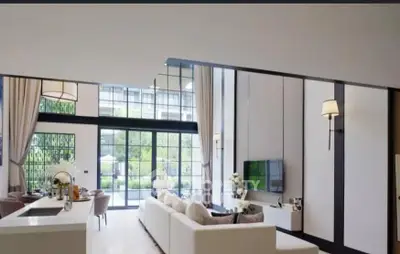 Luxurious modern living room with high ceilings and large windows offering garden views.