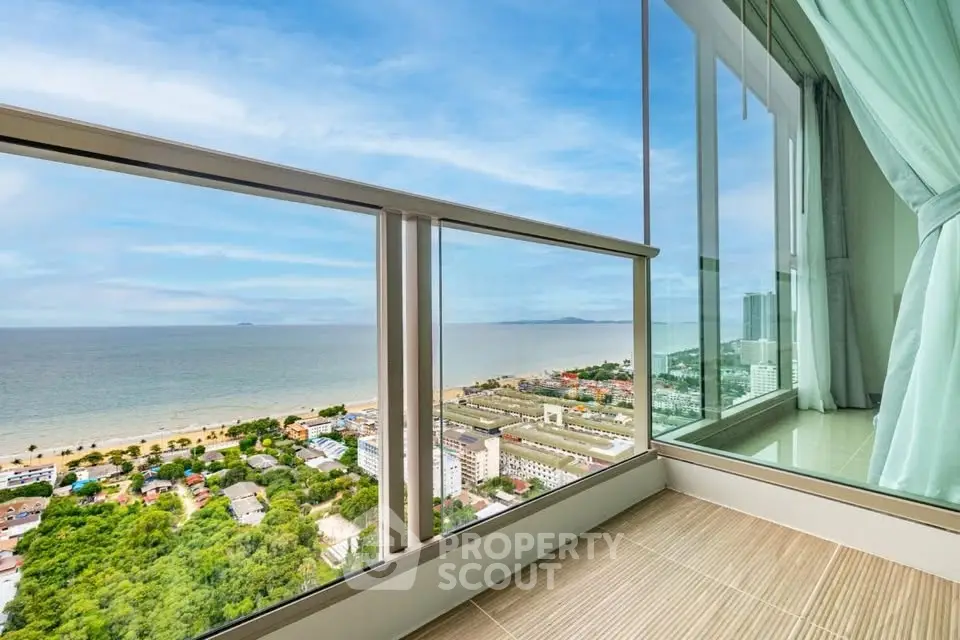 Stunning ocean view from high-rise balcony with glass railing and serene atmosphere.