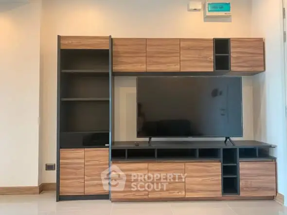 Modern living room with sleek wooden entertainment center and large flat-screen TV.