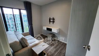 Modern living room with balcony view, featuring sleek furniture and mounted TV stand.