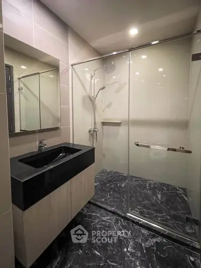 Modern bathroom with sleek black sink and spacious glass shower enclosure.