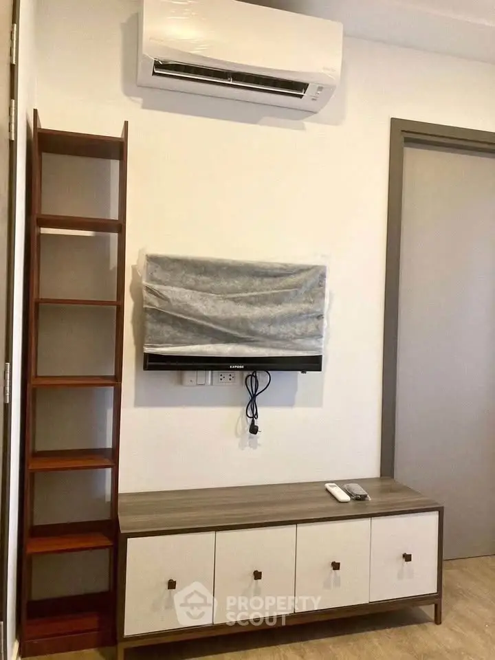 Modern living room with air conditioner and TV setup, featuring sleek wooden furniture and minimalist design.