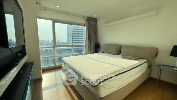 Spacious bedroom with large window offering stunning city views