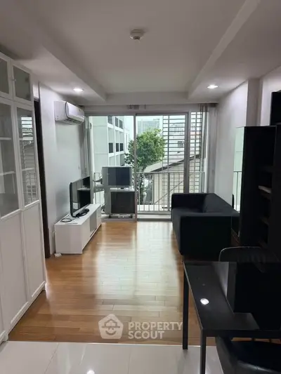 Modern living room with balcony view, featuring sleek furniture and natural light.