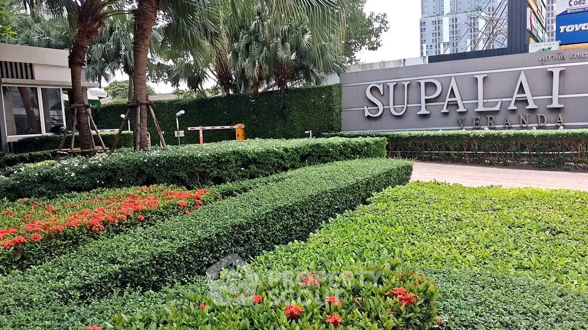 Lush garden entrance of Supalai Veranda with manicured hedges and vibrant flowers.