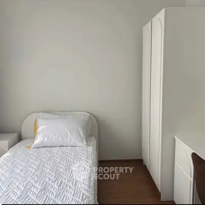 Cozy minimalist bedroom with single bed and white wardrobe, perfect for a serene living space.