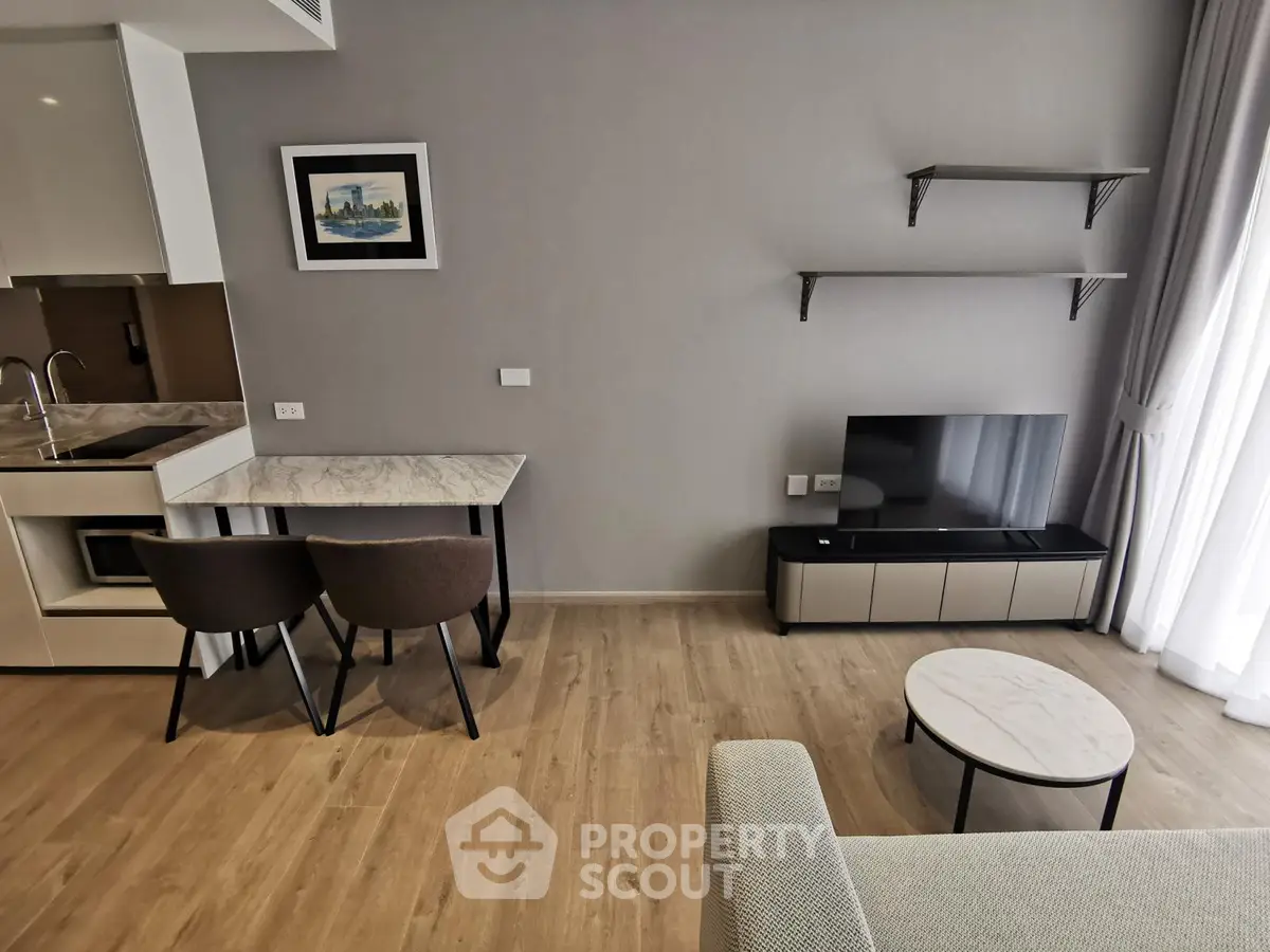 Modern living room with sleek furniture and open kitchen layout, featuring a cozy seating area and natural light.