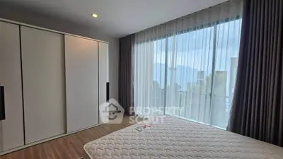 Spacious bedroom with large window and modern wardrobe in a stylish apartment.
