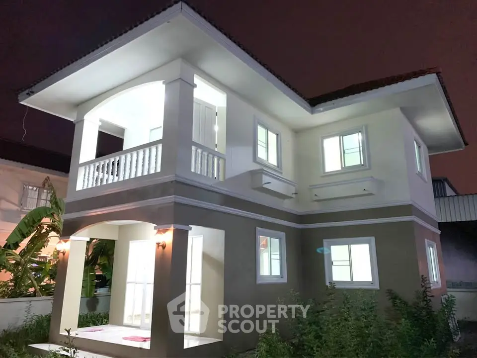 Stunning two-story modern house with illuminated windows and elegant balcony, perfect for family living.