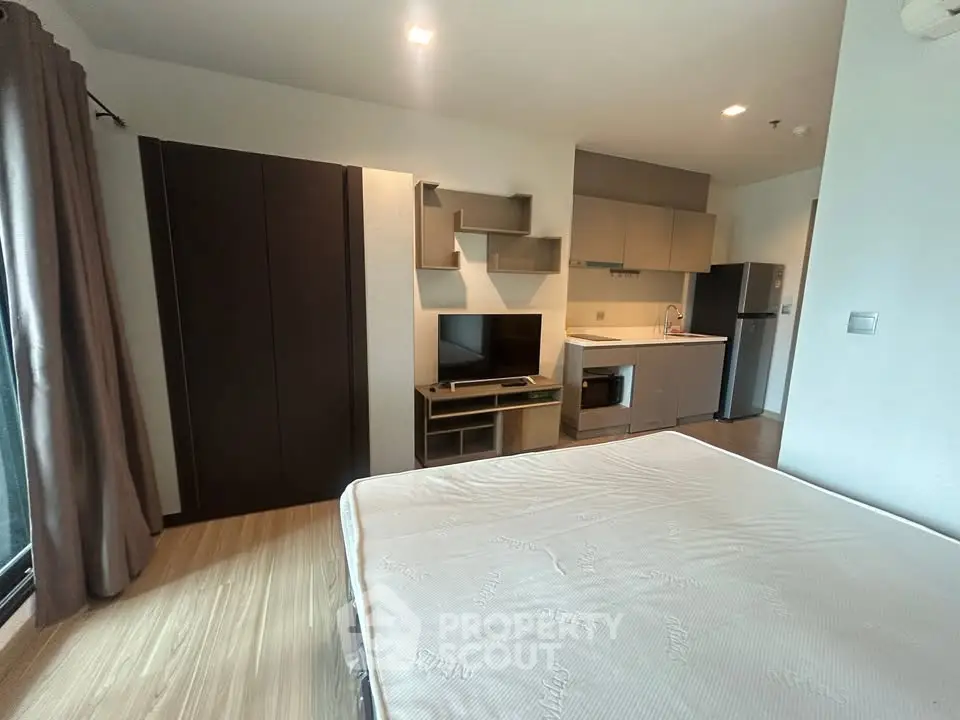 Modern studio apartment with integrated kitchen and cozy living area, featuring sleek cabinetry and natural light.