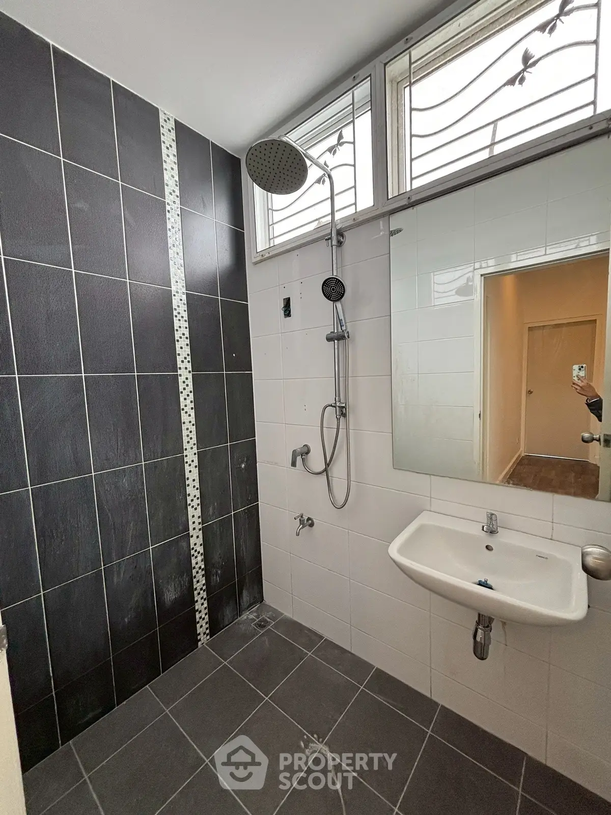 Modern bathroom with sleek black and white tiles and rainfall showerhead.