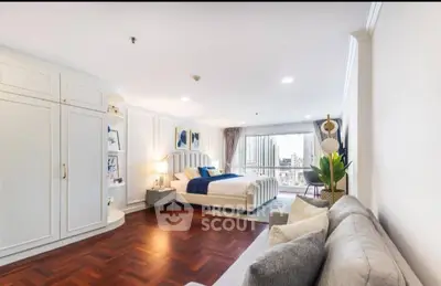Spacious bedroom with elegant decor and city view, featuring hardwood floors and cozy seating area.