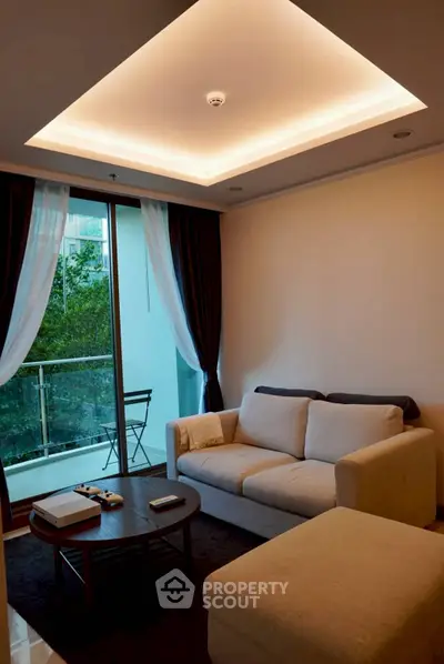 Modern living room with cozy sofa and elegant lighting, featuring a balcony with lush green views.