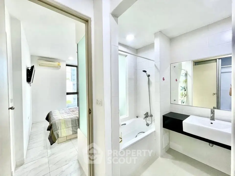 Modern apartment with sleek bathroom and cozy bedroom, featuring a bathtub and air conditioning.