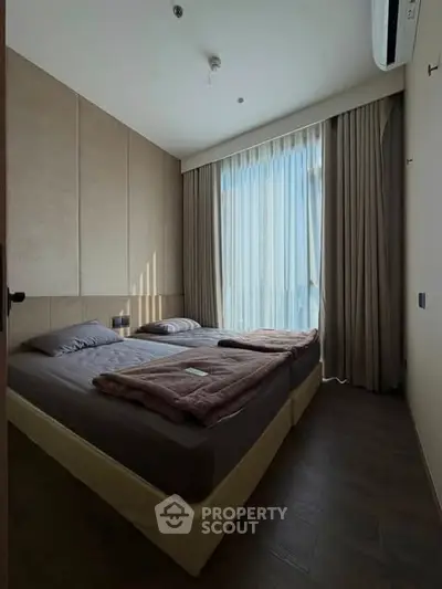Cozy bedroom with large window and modern decor, perfect for relaxation and comfort.