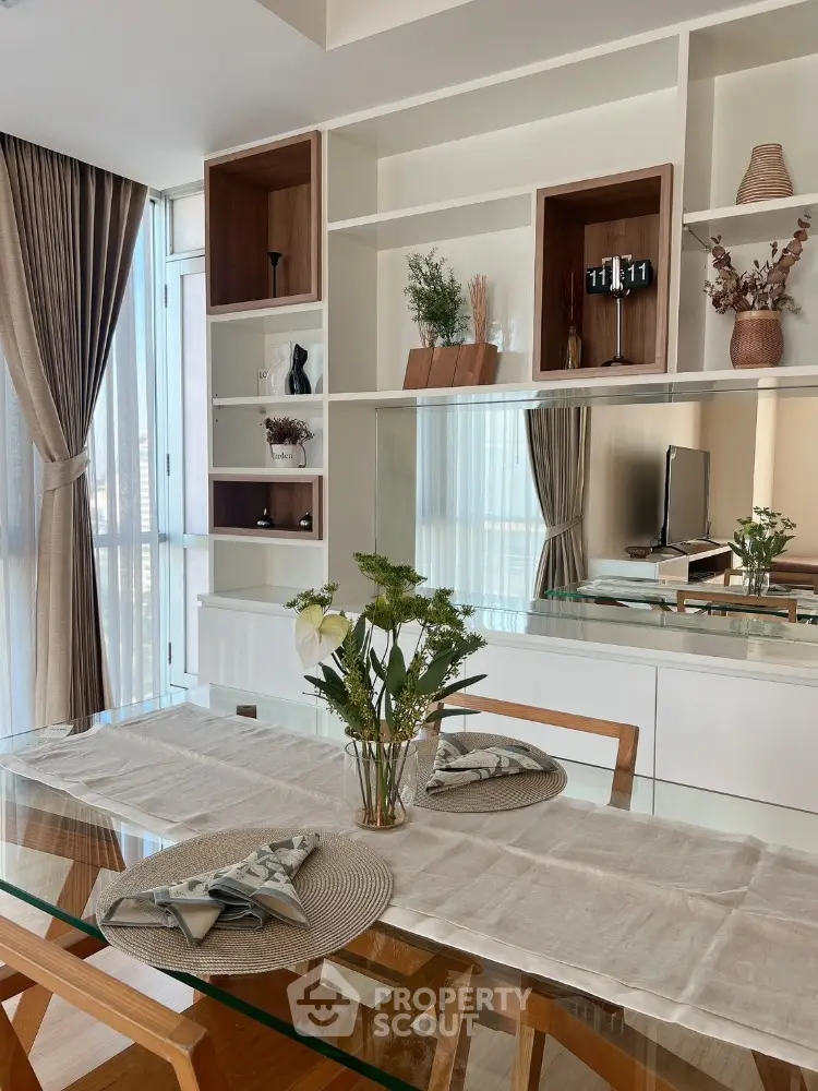 Elegant dining area with glass table and stylish shelving in modern apartment