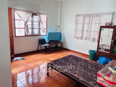Spacious bedroom with tiled floor and natural light, featuring a simple bed and window view.