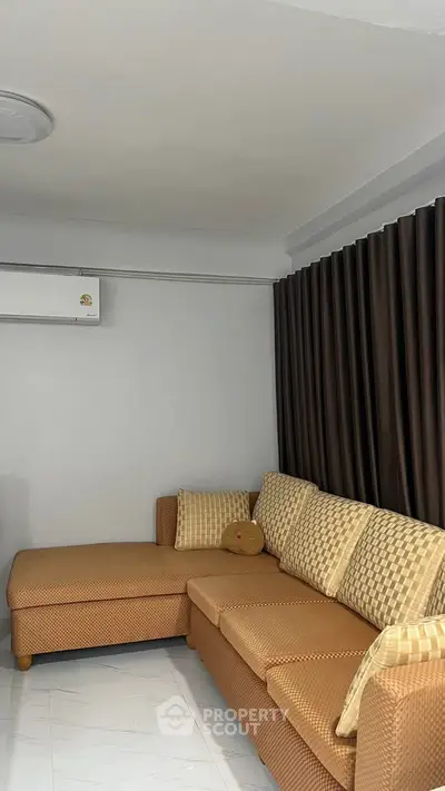 Cozy living room with stylish brown sofa and elegant curtains, perfect for relaxation.