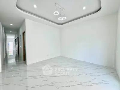 Spacious modern living room with elegant ceiling lights and glossy marble flooring.