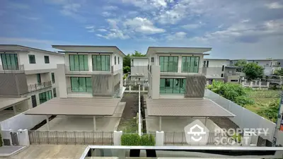 Modern two-story houses with large windows and carports in a serene neighborhood setting.