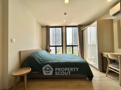 Spacious bedroom with large windows offering city views, modern furnishings, and ample natural light.
