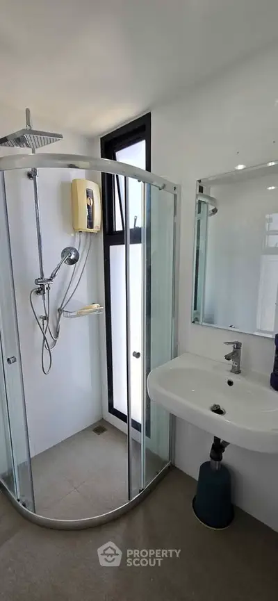 Modern bathroom with glass shower enclosure and sleek fixtures in a contemporary home.