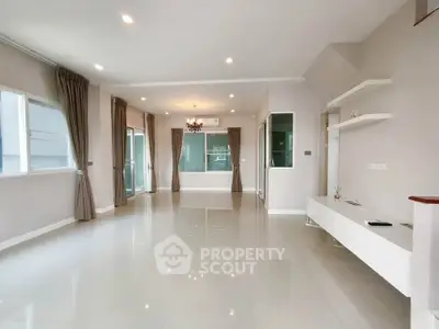 Spacious modern living room with large windows and elegant chandelier, perfect for family gatherings.