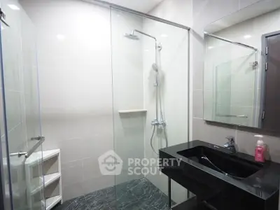 Modern bathroom with sleek black sink and glass shower enclosure