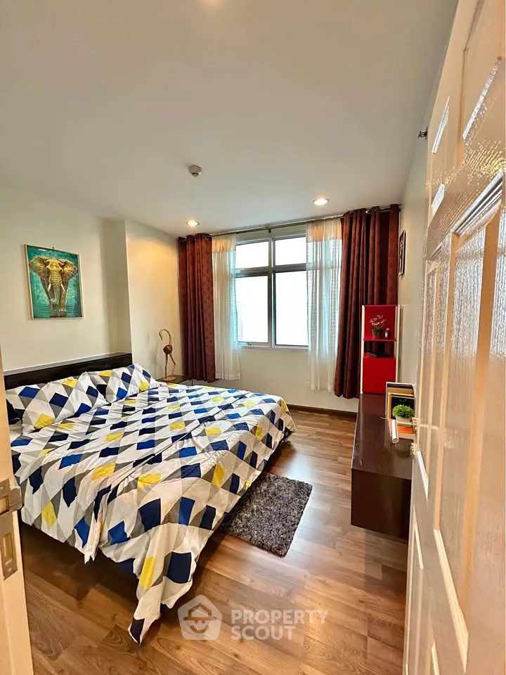 Spacious bedroom with modern decor and large window for natural light.