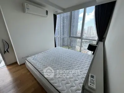 Modern bedroom with large windows offering stunning city views, featuring a comfortable bed and sleek air conditioning unit.