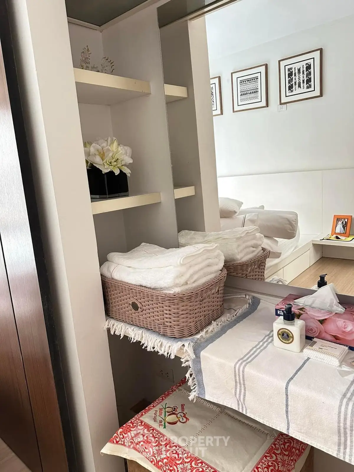 Cozy bedroom corner with decorative shelves and soft towels in a basket.