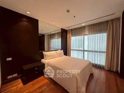 Luxurious bedroom with elegant dark wood accents and large window for natural light.
