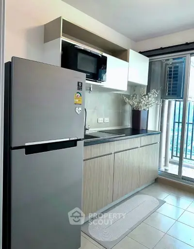 Modern kitchen with sleek fridge and microwave, featuring a stylish open layout and balcony view.
