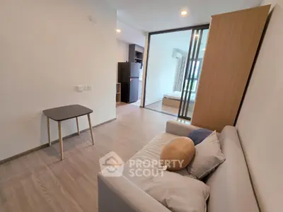 Modern apartment interior with cozy living room and bedroom view, featuring sleek furniture and open layout.