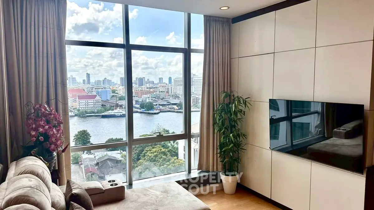 Luxurious living room with stunning city and river view through large windows, featuring modern decor and cozy seating.